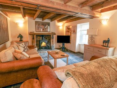 A living room with sofas a coffee table a fireplace and a television at The Nook at 29 High Street Cloughton near Burniston