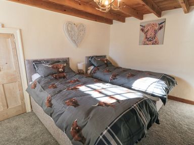 A bedroom with two single beds with animal print bedding and a heart decoration on the wall at The Nook at 29 High Street Cloughton near Burniston