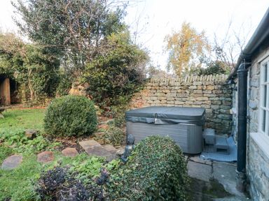 A garden with a covered hot tub stone steps bushes and a stone wall at The Nook at 29 High Street Cloughton near Burniston