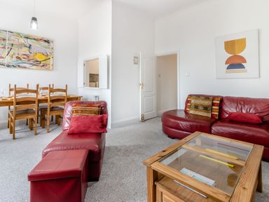 A living room with red leather sofas wooden dining table and glass top wooden coffee table at Barwood View in Torquay