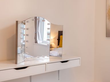 A white floating vanity table with a tri-fold lighted mirror in a bedroom at Barwood View in Torquay