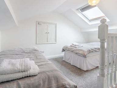 A bedroom with two single beds with towels on them a skylight window and a small cabinet on the wall at Barwood View in Torquay