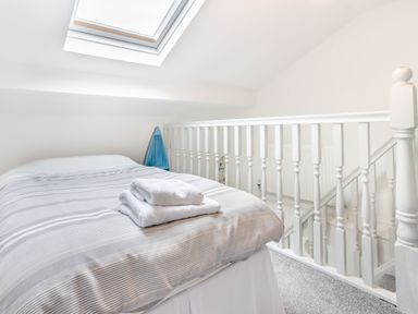A bedroom with a bed and towels on it under a skylight by a white railing at Barwood View in Torquay