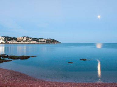 A coastal view with calm water rocks and buildings in the distance at Barwood View in Torquay