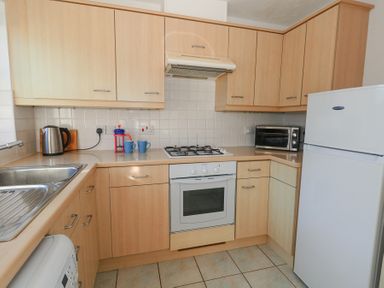 A kitchen with wooden cabinets a sink stove oven refrigerator toaster kettle and mugs at Fairways in Wyke Regis