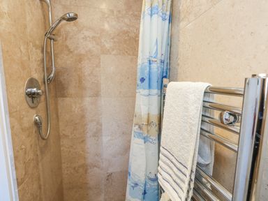 A shower area with a showerhead curtain and towel on a chrome towel rack at Fairways in Wyke Regis