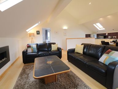 A living room with black sofas and a tile coffee table at Cholwell Barn Apartment in Mary Tavy