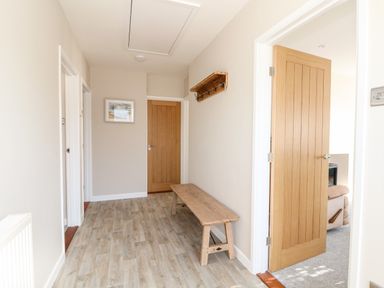 A hallway with a wooden bench a wall-mounted coat rack and wooden doors at Sunnyside in Wells-Next-The-Sea