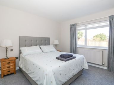 A bedroom with a double bed bedside tables lamps and a window with curtains at Sunnyside in Wells-Next-The-Sea