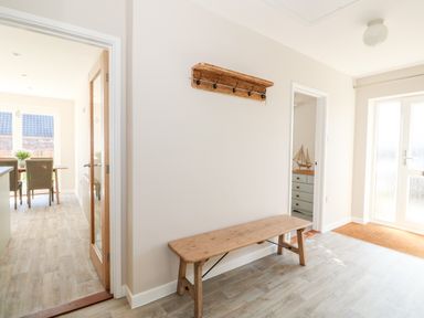 An entryway with a wooden bench and wall-mounted coat rack next to a door leading to a dining area at Sunnyside in Wells-Next-The-Sea