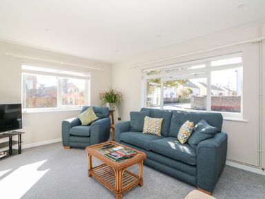 A living room with blue sofa armchair and wicker coffee table with magazines at Sunnyside in Wells-Next-The-Sea