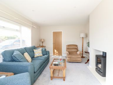 A living room with blue sofa beige armchair and a wood stove at Sunnyside in Wells-Next-The-Sea