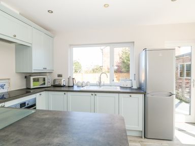 A kitchen with light cabinets a sink microwave toaster electric kettle and refrigerator at Sunnyside in Wells-Next-The-Sea