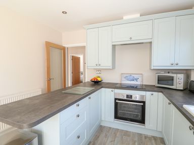 A kitchen with light blue cabinets a built-in oven a microwave and a fruit bowl at Sunnyside in Wells-Next-The-Sea