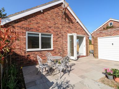 A brick house with a patio table and four chairs outside and an open door at Sunnyside in Wells-Next-The-Sea