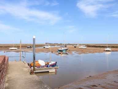 A river with boats on mudflats and a concrete jetty at Sunnyside in Wells-Next-The-Sea