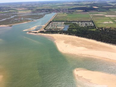 An aerial view of a coastal area with sandy beaches water and green fields at Sunnyside in Wells-Next-The-Sea