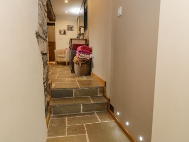 A hallway with stone steps leading to a seating area with a chair and folded blankets at Hen Dy Craig Yr Ronwy Capel Celyn near Bala