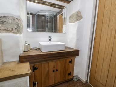 A bathroom with a wooden vanity unit with a rectangular white sink and a large mirror above at Hen Dy Craig Yr Ronwy in Capel Celyn near Bala
