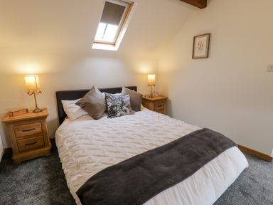 A bedroom with a double bed between two wooden nightstands with lamps and a skylight window at Hen Dy Craig Yr Ronwy in Capel Celyn near Bala