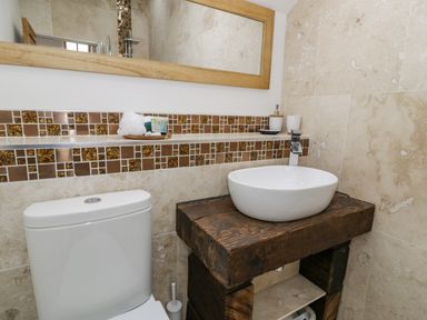 A bathroom with a toilet and a wooden vanity with a white basin sink at Hen Dy Craig Yr Ronwy in Capel Celyn near Bala