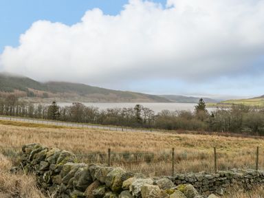 A rural landscape with a stone wall in the foreground a road trees hills and a lake at Hen Dy Craig Yr Ronwy Capel Celyn near Bala