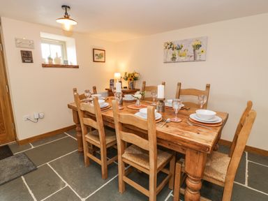 A dining room with a wooden table set with plates glasses and candles at Hen Dy Craig Yr Ronwy in Capel Celyn near Bala