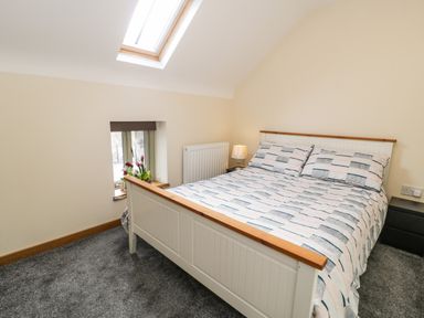 A bedroom with a double bed next to a window and skylight at Hen Dy Craig Yr Ronwy in Capel Celyn near Bala