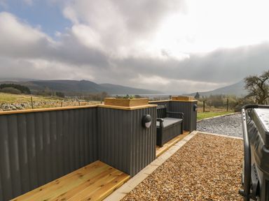 An outdoor seating area with a bench and planters surrounded by wooden panels at Hen Dy Craig Yr Ronwy in Capel Celyn near Bala