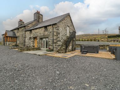 A stone house with gravel driveway and outdoor hot tub at Hen Dy Craig Yr Ronwy in Capel Celyn near Bala