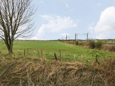 A field with a tree and a fence near railway tracks at Holida Hoose in Belford