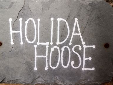 A stone slab with the words Holida Hoose painted in white