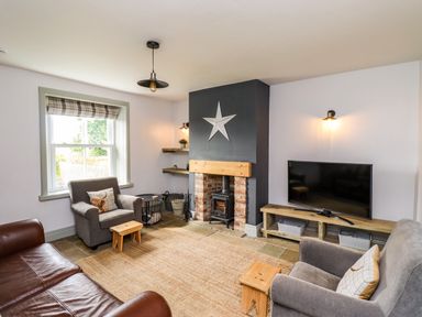 A living room with a fireplace TV sofa and armchairs at Holida Hoose in Belford