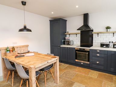 A kitchen with wooden dining table and chairs blue cabinets and oven at Holida Hoose in Belford