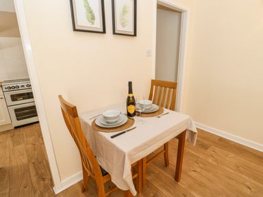 A dining area with a table set for two with plates bowls wine glasses and a bottle of prosecco at 1 The Stables in Alston