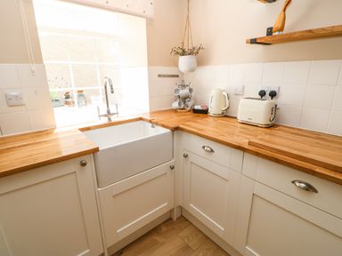 A kitchen corner with a sink under a window a kettle a toaster and hanging plant at 1 The Stables in Alston