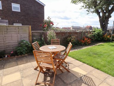A garden with a wooden table and chairs at The Nest in Beadnell