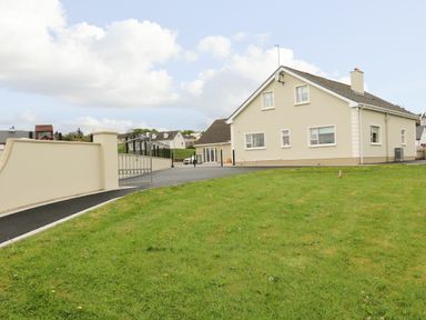 A house with a driveway and a lawn surrounded by a wall and gate at Loughanure Lake View in Loughanure County Donegal