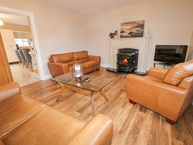 A living room with brown leather sofas a glass coffee table a fireplace and a television at Loughanure Lake View in Loughanure County Donegal