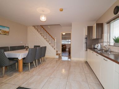 A kitchen with a dining table and chairs next to stairs at Loughanure Lake View in Loughanure County Donegal