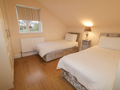 A bedroom with two single beds a bedside table with a lamp a window and wardrobe at Loughanure Lake View in Loughanure County Donegal