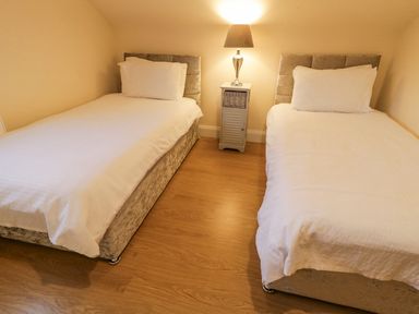 A bedroom with two single beds and a nightstand with a lamp in between at Loughanure Lake View in Loughanure County Donegal