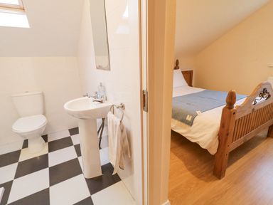A bathroom with a toilet and sink next to a bedroom with a wooden bed frame at Loughanure Lake View in Loughanure County Donegal