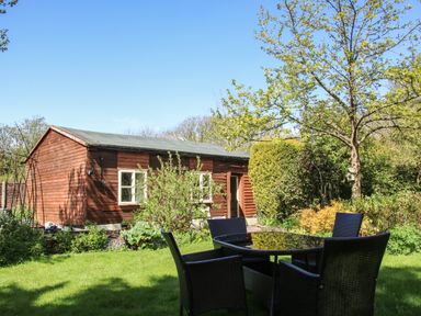 A garden with a wooden shed and outdoor table with chairs at The Garden Lodge in Upton Cressett near Bridgnorth