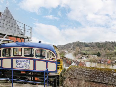 A blue and cream railway carriage on a track with a river and houses in the background at The Garden Lodge in Upton Cressett near Bridgnorth