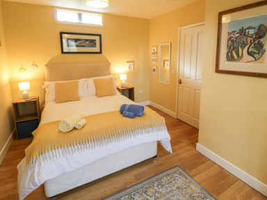 A bedroom with a bed towels on it two bedside tables lamps and framed paintings at The Garden Lodge in Upton Cressett near Bridgnorth