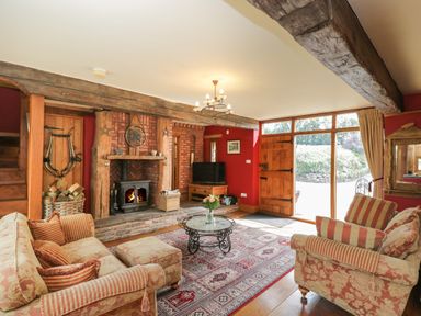 A living room with sofas a glass coffee table and fireplace at Pentre Barn in Llantilio Pertholey near Mardy