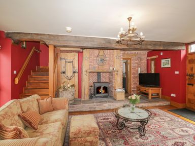 A living room with a fireplace wood stove television and floral sofa at Pentre Barn in Llantilio Pertholey near Mardy