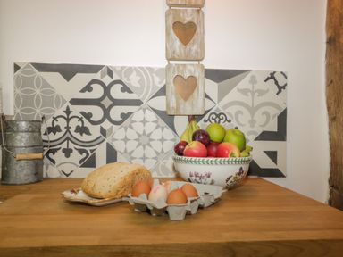 A kitchen countertop with bread a carton of eggs a bowl of fruit and a metal canister with wooden handle at Pentre Barn Llantilio Pertholey near Mardy
