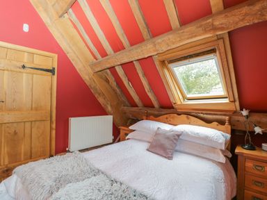 A bedroom with a bed and a window under a slanted ceiling at Pentre Barn in Llantilio Pertholey near Mardy